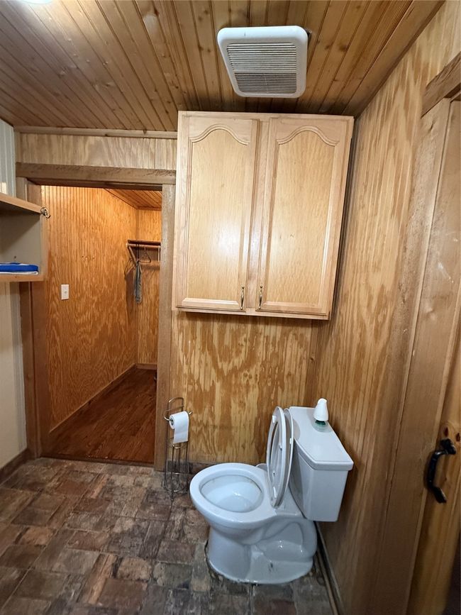 Bathroom featuring toilet, wood walls, and wooden ceiling | Image 14