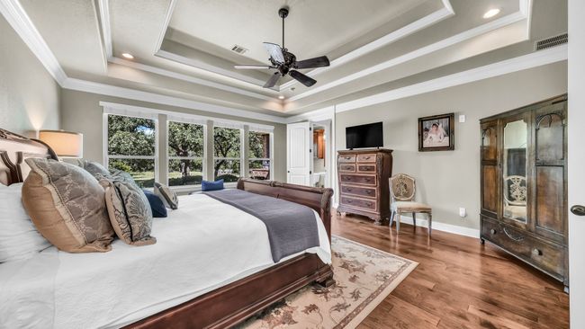 Bedroom with a raised ceiling, ornamental molding, wood finished floors, ceiling fan, and recessed lighting | Image 29