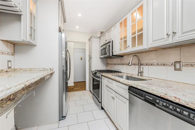 Kitchen featuring stainless steel appliances, tasteful backsplash, light stone countertops, recessed lighting, and glass insert cabinets | Image 18