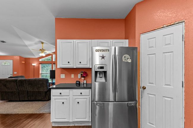 Kitchen with stainless steel fridge, wood finished floors, vaulted ceiling, white cabinetry, and ceiling fan | Image 11