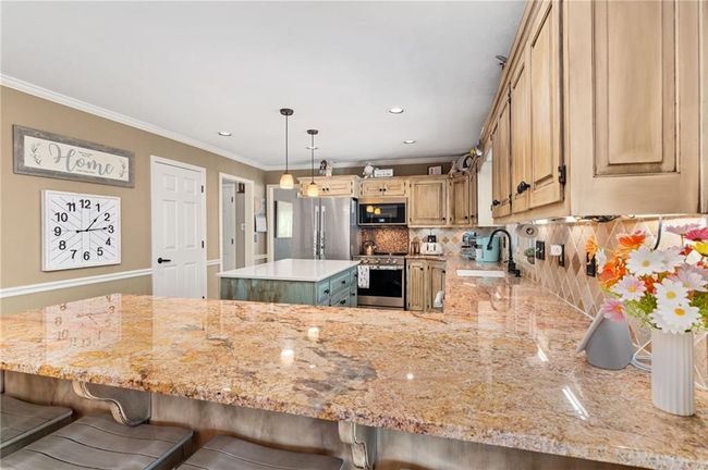 Kitchen with sink, crown molding, light brown cabinets, kitchen peninsula, and stainless steel appliances | Image 13