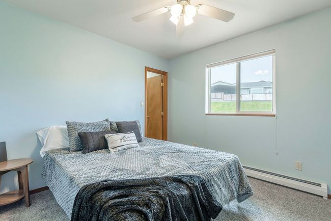 Carpeted bedroom with a baseboard heating unit and ceiling fan | Image 13