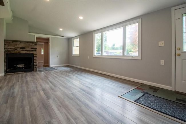Unfurnished living room featuring a fireplace, wood-type flooring, and lofted ceiling | Image 4