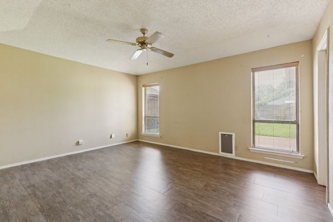 Empty room with ceiling fan, dark wood-style flooring, healthy amount of natural light, and a textured ceiling | Image 18