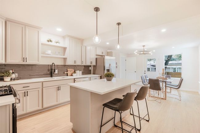 Kitchen featuring refrigerator with ice dispenser, light wood-style flooring, decorative backsplash, a chandelier, and recessed lighting | Image 8