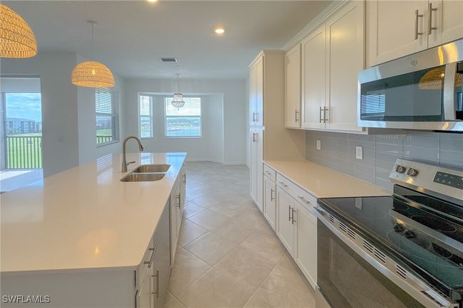 Kitchen with appliances with stainless steel finishes, a sink, backsplash, light countertops, and white cabinets | Image 4