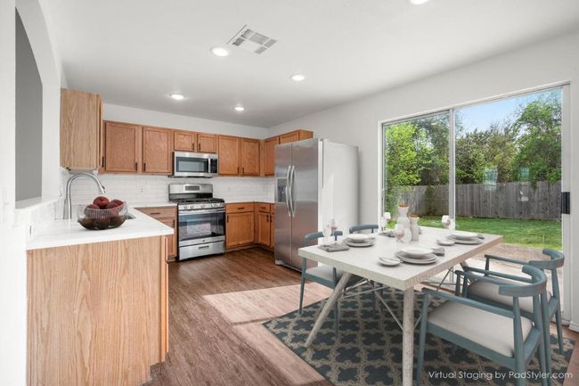 Virtually staged Kitchen featuring light countertops, wood finished floors, stainless steel appliances, visible vents, and decorative backsplash | Image 7