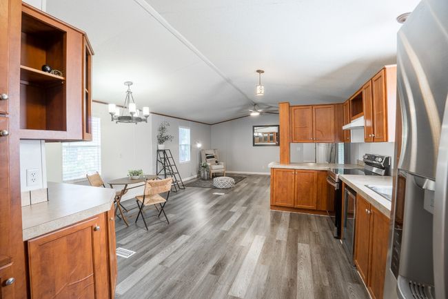 Kitchen featuring stainless steel appliances, open shelves, light countertops, light wood-type flooring, and ceiling fan | Image 11