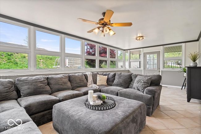 living area with light tile patterned flooring, a ceiling fan, and baseboards | Image 9