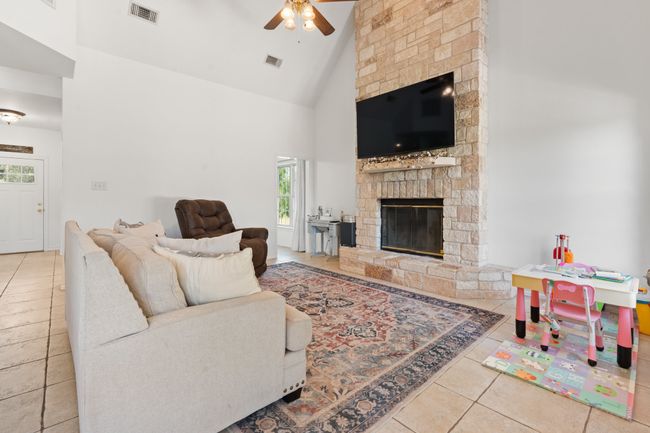 Living room featuring a ceiling fan, high vaulted ceiling, tile patterned flooring, and a fireplace | Image 9