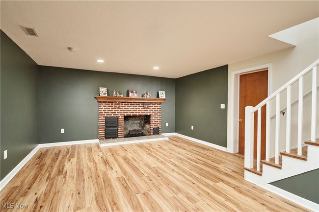 Unfurnished living room featuring light wood-style floors, stairs, a brick fireplace, baseboards, and recessed lighting | Image 21