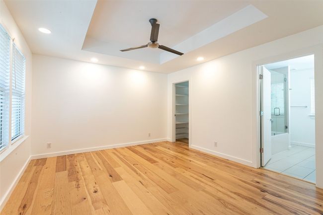 Unfurnished room featuring a raised ceiling, light wood-type flooring, ceiling fan, and recessed lighting | Image 21