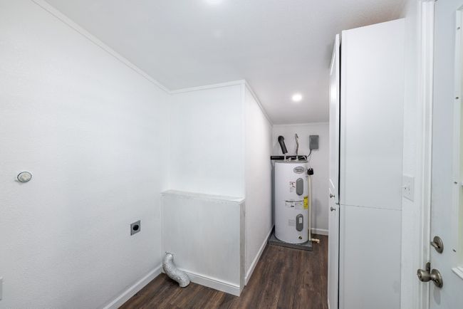 Laundry room with hookup for an electric dryer, water heater, dark wood-style flooring, crown molding, and laundry area | Image 22