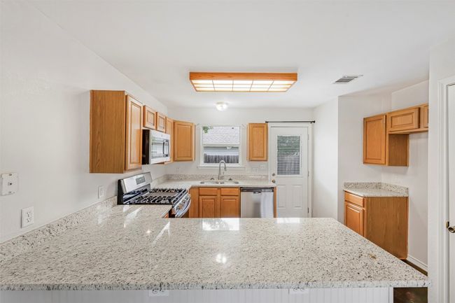 Kitchen featuring appliances with stainless steel finishes, a peninsula, and light stone countertops | Image 10
