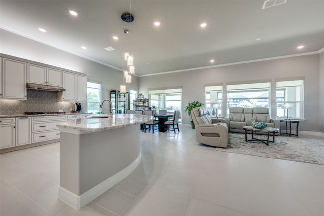 Kitchen with pendant lighting, Dolomite countertops, and a kitchen island with sink, overlooking living room and dining area | Image 5