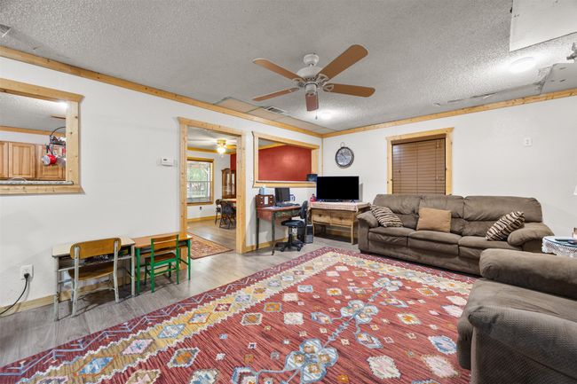 Living area with ceiling fan, wood finished floors, a textured ceiling, and baseboards | Image 19