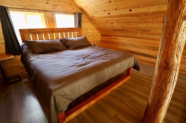 Bedroom featuring wooden walls, hardwood / wood-style flooring, and vaulted ceiling | Image 39