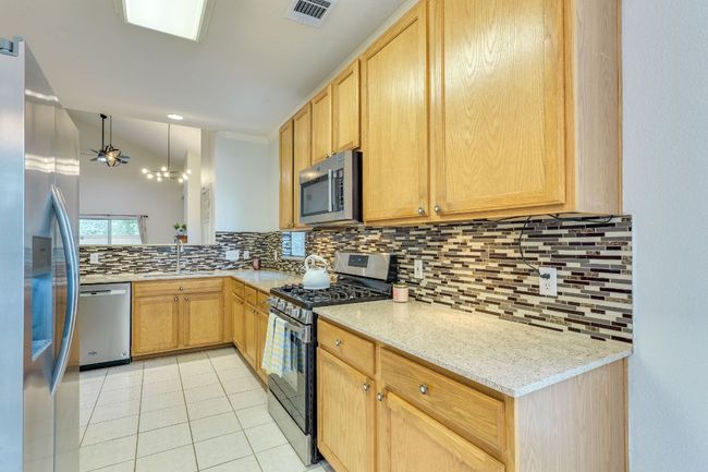 Kitchen featuring appliances with stainless steel finishes, tasteful backsplash, light tile patterned floors, and light brown cabinetry | Image 16