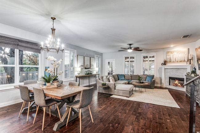 Dining area with a glass covered fireplace, dark wood-type flooring, a chandelier, and ceiling fan | Image 14