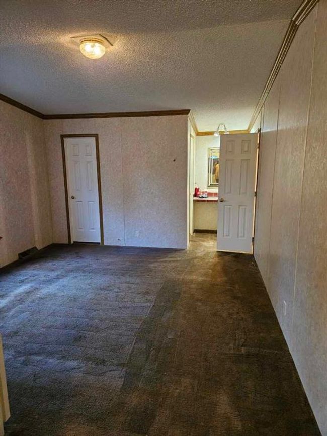 Unfurnished bedroom featuring a textured ceiling, dark colored carpet, and ornamental molding | Image 31