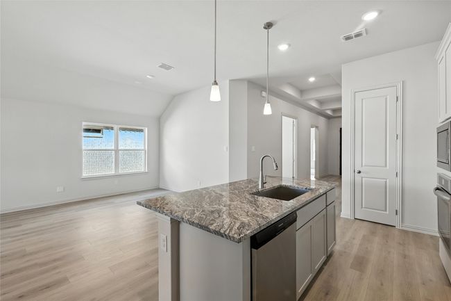 Kitchen with stainless steel appliances, light wood finished floors, a center island with sink, light stone counters, and recessed lighting | Image 6