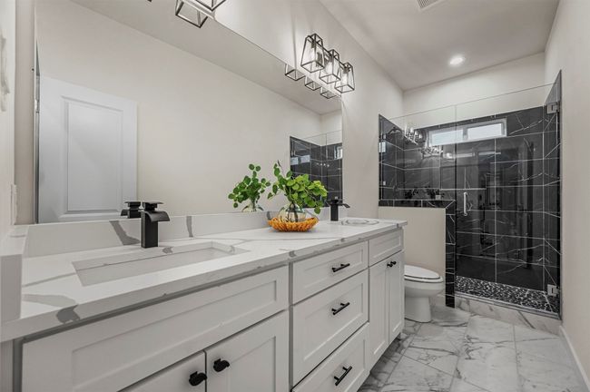 Full bathroom featuring a shower stall, double vanity, marble finish floor, toilet, and a sink | Image 24
