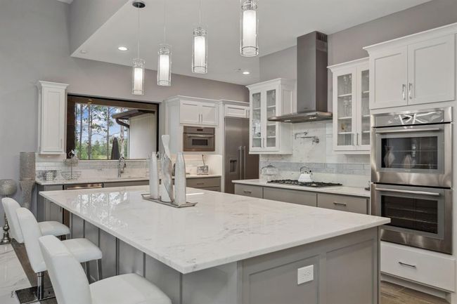 Enhanced by ample lighting, striking pendant fixtures, and a bold statement piece, this kitchen exudes a unique and stylish charm. | Image 15