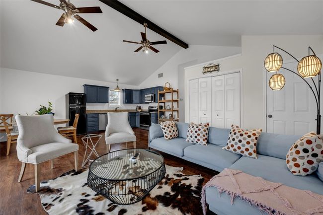 Living area with high vaulted ceiling, a ceiling fan, wood finished floors, and beamed ceiling | Image 9