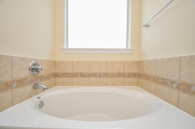 This primary bathroom features a spacious bathtub with elegant tile detailing and a bright window, creating a serene and inviting atmosphere. | Image 20