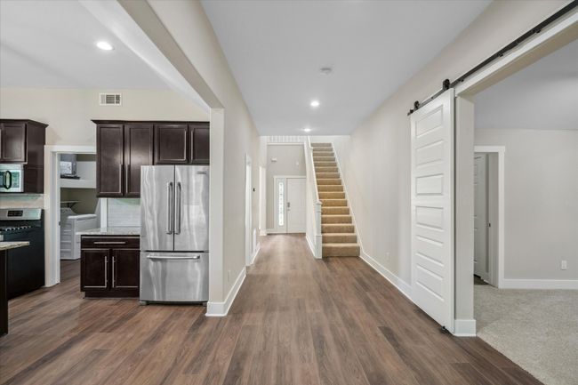 Kitchen with stainless steel appliances, a barn door, dark brown cabinets, dark wood-type flooring, and recessed lighting | Image 21