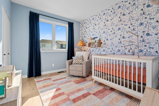 Bedroom featuring visible vents, a crib, wallpapered walls, baseboards, and wood finished floors | Image 21