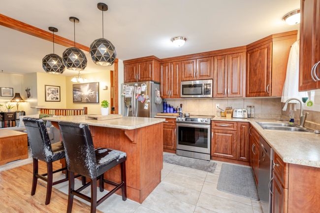 Kitchen featuring stainless steel appliances, a kitchen breakfast bar, a center island, open floor plan, and hanging light fixtures | Image 8