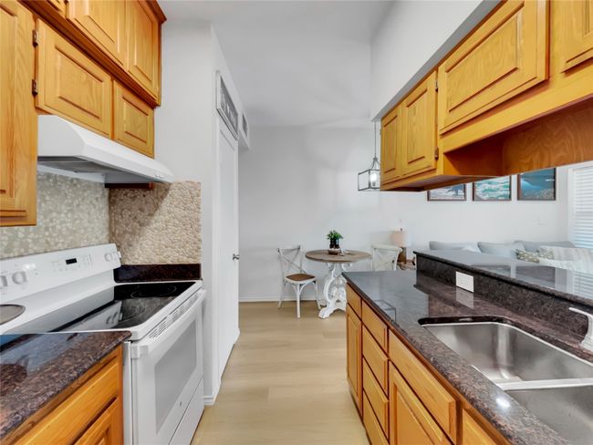 Kitchen featuring electric stove, under cabinet range hood, a sink, backsplash, and light wood-type flooring | Image 12