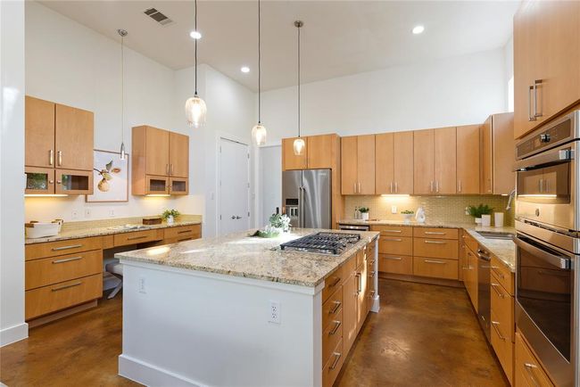 Kitchen featuring stainless steel appliances, a high ceiling, a sink, finished concrete flooring, and backsplash | Image 12