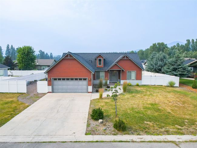 View of front facade featuring a front yard, an attached garage, fence, and driveway | Image 13