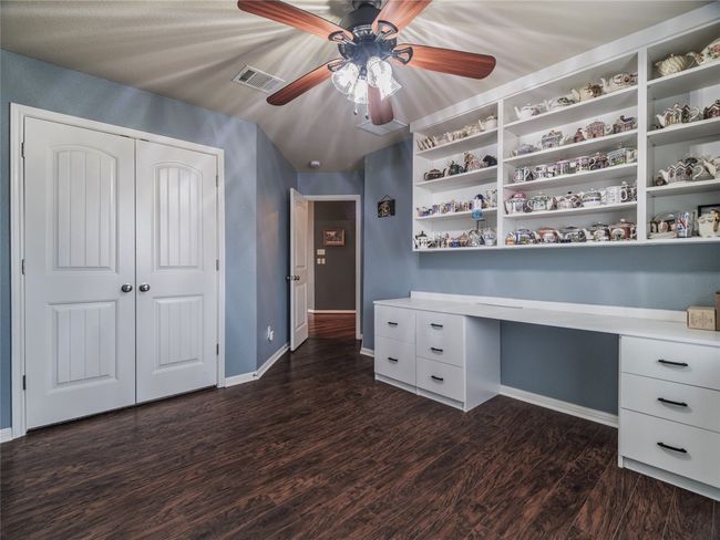 Unfurnished office featuring ceiling fan, baseboards, dark wood finished floors, and built in study area | Image 14