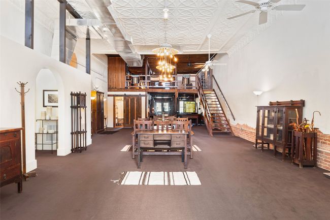Dining area featuring arched walkways, ceiling fan with notable chandelier, a high ceiling, carpet flooring, and stairs | Image 7