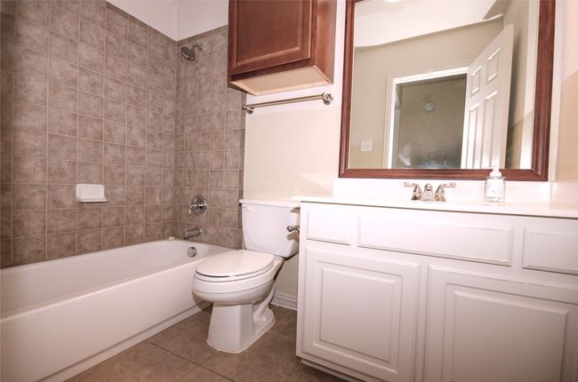 Full bathroom with toilet, tile patterned floors, vanity, and washtub / shower combination | Image 20