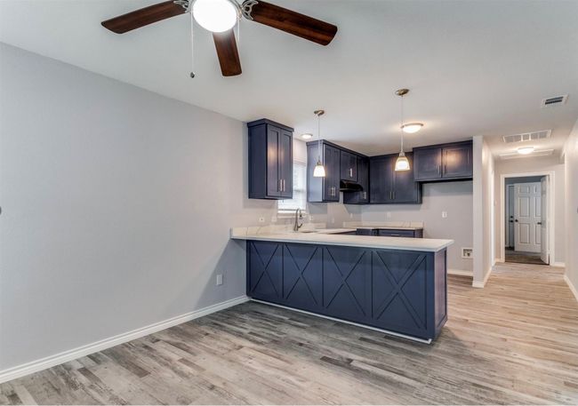 Kitchen featuring visible vents, a peninsula, and light wood-style flooring | Image 8