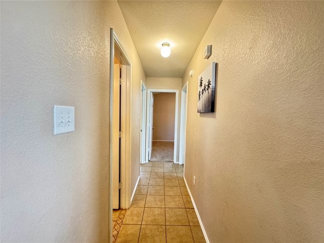 Hall featuring a textured wall, light tile patterned flooring, and a textured ceiling | Image 19
