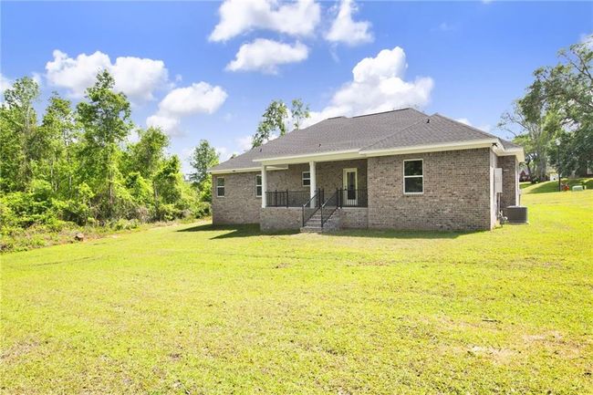 Back of property with a yard, brick siding, cooling unit, and a shingled roof | Image 30