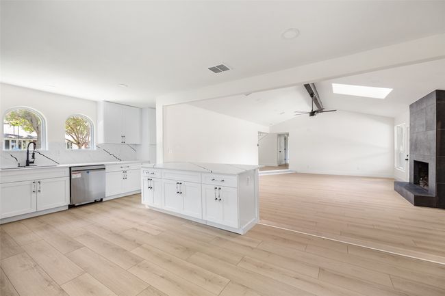 Kitchen with white cabinetry, a ceiling fan, light stone counters, a skylight, and light wood-type flooring | Image 11