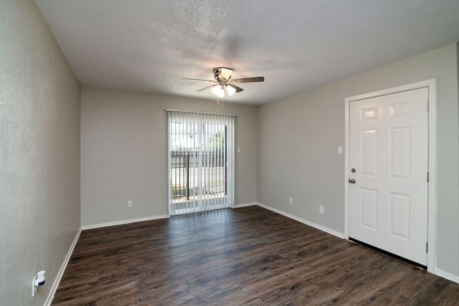 Empty room with dark wood-style floors, a ceiling fan, and baseboards | Image 9