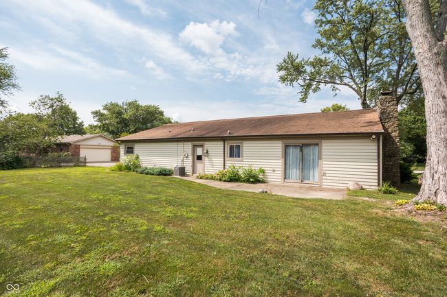 rear view of house featuring a yard, a chimney, a patio, and a garage | Image 37