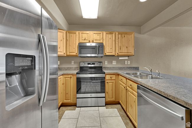 Kitchen featuring stainless steel appliances, light brown cabinetry, and light tile patterned floors | Image 4
