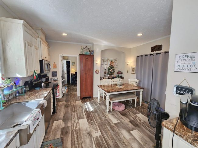Kitchen with a textured ceiling, ornamental molding, stainless steel appliances, and dark wood-type flooring | Image 8