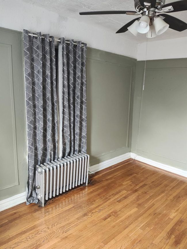 Empty room with baseboards, wood finished floors, and radiator | Image 18