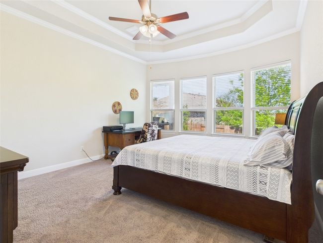 Bedroom featuring baseboards, crown molding, carpet floors, and a raised ceiling | Image 11