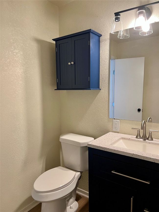 Half bathroom featuring vanity, wood finished floors, and a textured wall | Image 27