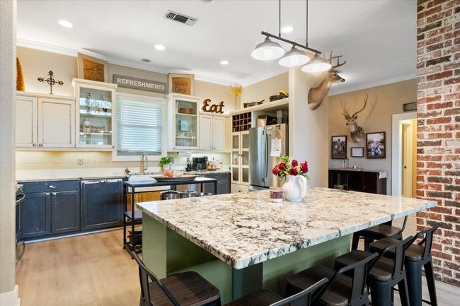 Kitchen with freestanding refrigerator, a kitchen bar, a sink, light wood-style floors, and crown molding | Image 9